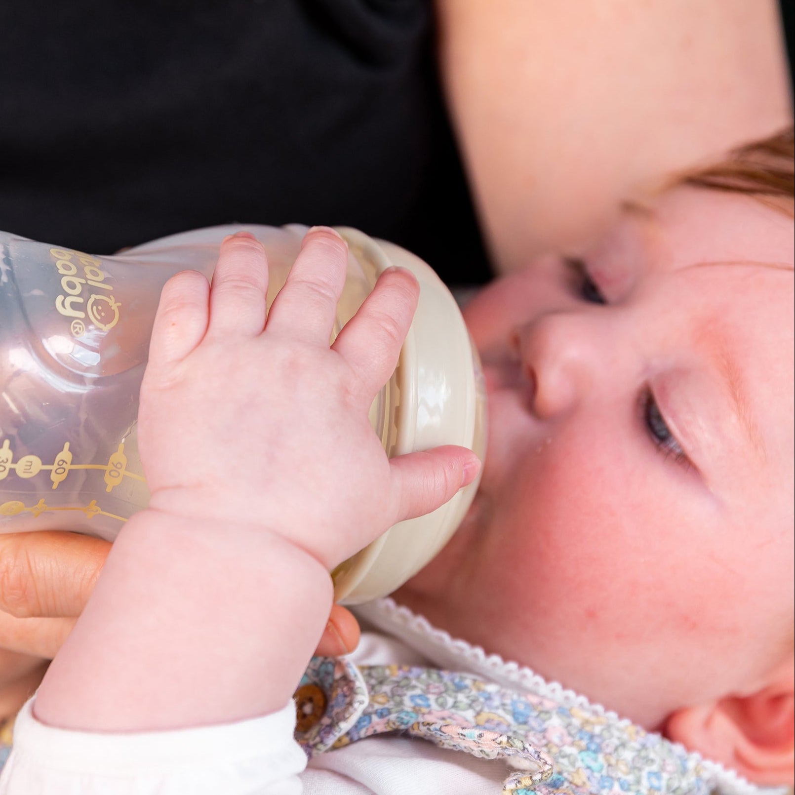 Baby holding a bottle, close-up shot.